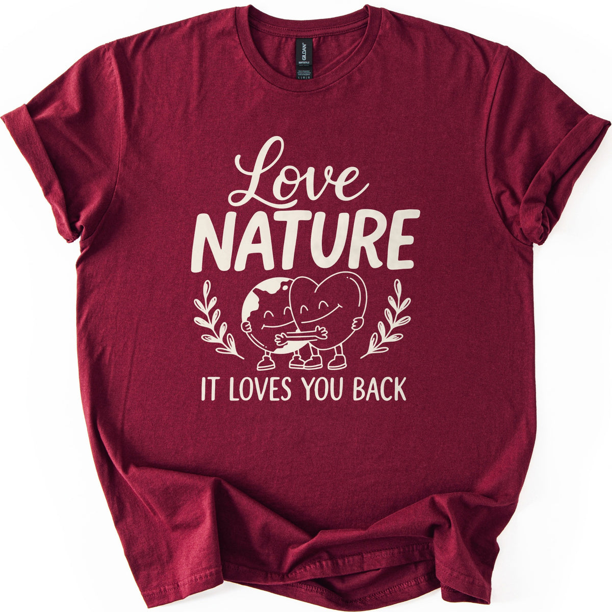 Nature Loves You Back Comfort Colors T-shirt in Maroon, laid flat. Cream print reads Love NATURE above a smiling cartoon Earth and heart hugging between two leafy sprigs, then IT LOVES YOU BACK. The sleeves are rolled and the shirt lies on a white background.