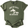 Be Superior Comfort Colors T-shirt in Military Green, laid flat. A cream print shows the words Don't Be Salty, arched over a silhouette of the Great Lakes with a small crown above Lake Superior, and Be Superior below. Sleeves are cuffed on a white background.