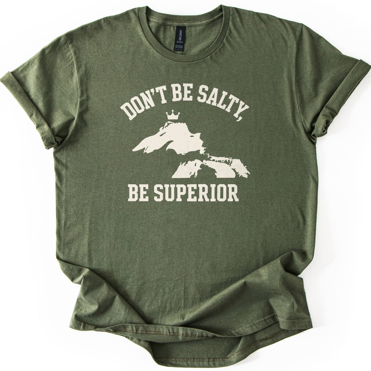 Be Superior Comfort Colors T-shirt in Military Green, laid flat. A cream print shows the words Don't Be Salty, arched over a silhouette of the Great Lakes with a small crown above Lake Superior, and Be Superior below. Sleeves are cuffed on a white background.