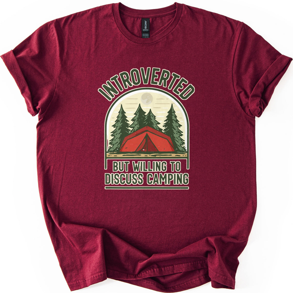 Introverted Camping Comfort Colors T-shirt in Maroon, laid flat. An arched badge shows a red tent among green pine trees under a pale moon, with INTROVERTED curved above and BUT WILLING TO DISCUSS CAMPING below in cream letters. The shirt lies on a white background.