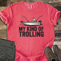 My Kind Of Trolling Comfort Colors T-shirt in Watermelon, laid flat. A man in a cap holds a cup in a small fishing boat with two bent rods and motors, above the words My Kind Of Trolling in black. Olive cargo pants and brown hiking boots sit beside it on weathered wood.
