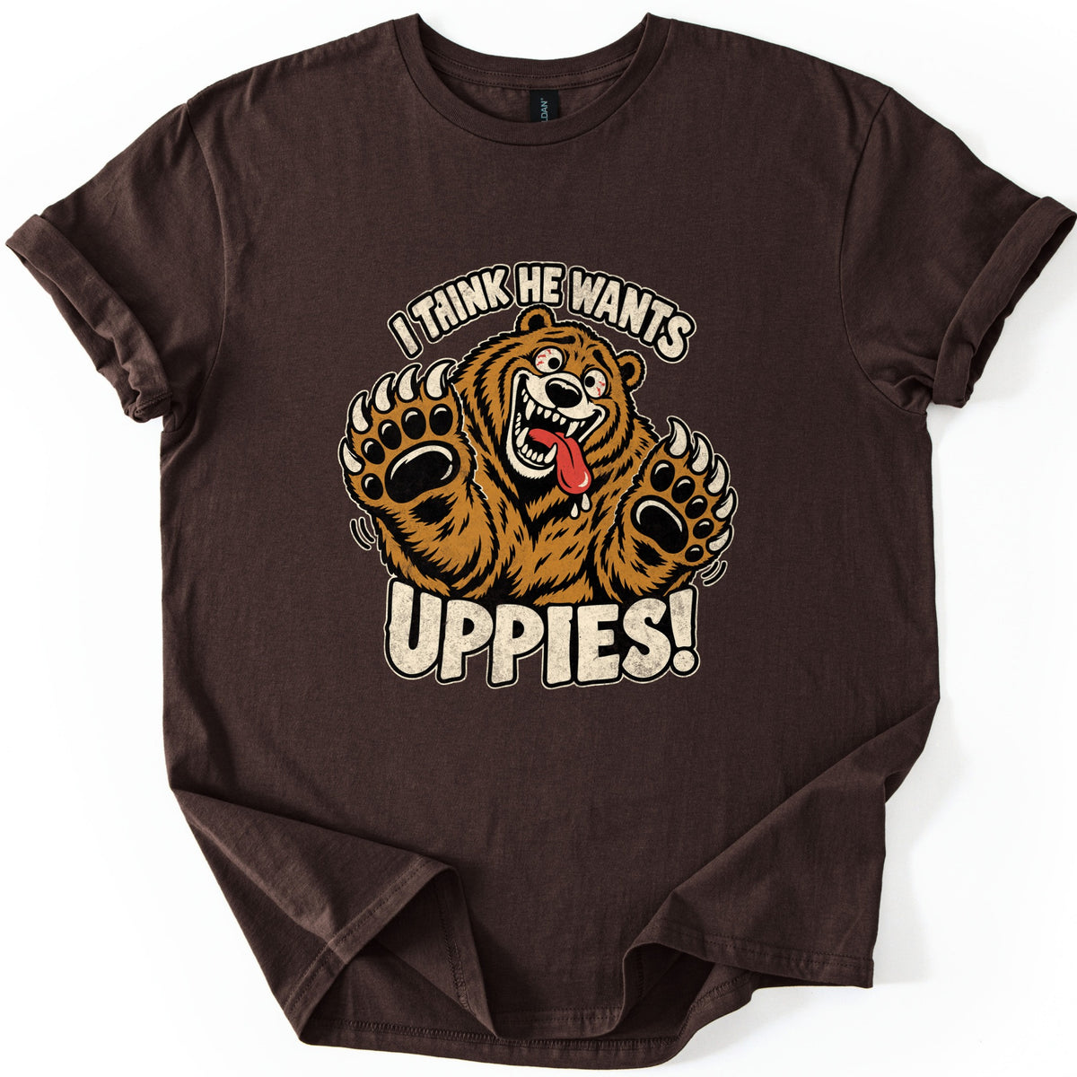 I Think He Wants Uppies Comfort Colors T-shirt in Dark Chocolate, laid flat. A cartoon brown bear with bulging eyes, a toothy grin and a drooling tongue reaches up with both clawed paws between the words I Think He Wants and Uppies! The sleeves are cuffed on a white background.
