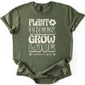 Plant Trees Grow Love Comfort Colors T-shirt in Military Green, laid flat. Cream retro bubble letters read Plant Trees Grow Love, with a smiling daisy beside Plant and Love Blooms in Green between two small flowers below. Sleeves are rolled on a white background.