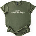 Camper Heartbeat Comfort Colors T-shirt in Military Green, laid flat. A cream line drawing of a small camper trailer with a window, door, wheel and hitch jack sits in the middle of a heartbeat line across the chest, with no words. The sleeves are cuffed on a white background.
