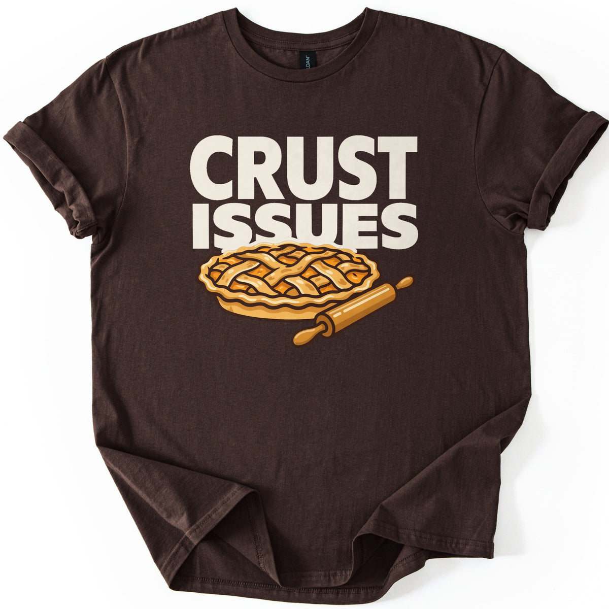 Crust Issues Comfort Colors T-shirt in Dark Chocolate, laid flat. Cream block letters read CRUST ISSUES above a cartoon lattice-top pie with a wooden rolling pin. The shirt has rolled sleeves and lies on a plain white background.