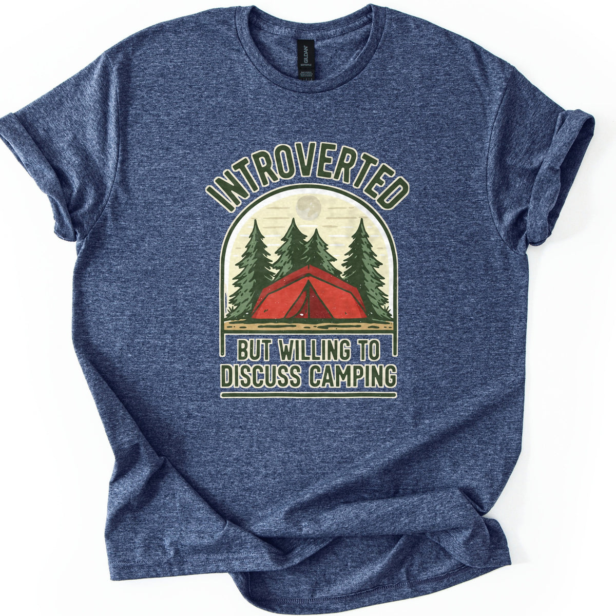 Introverted Camping Comfort Colors T-shirt in Heather Navy, laid flat. An arched badge shows a red tent among green pine trees under a pale moon, with INTROVERTED curved above and BUT WILLING TO DISCUSS CAMPING below. The shirt lies on a white background with rolled sleeves.
