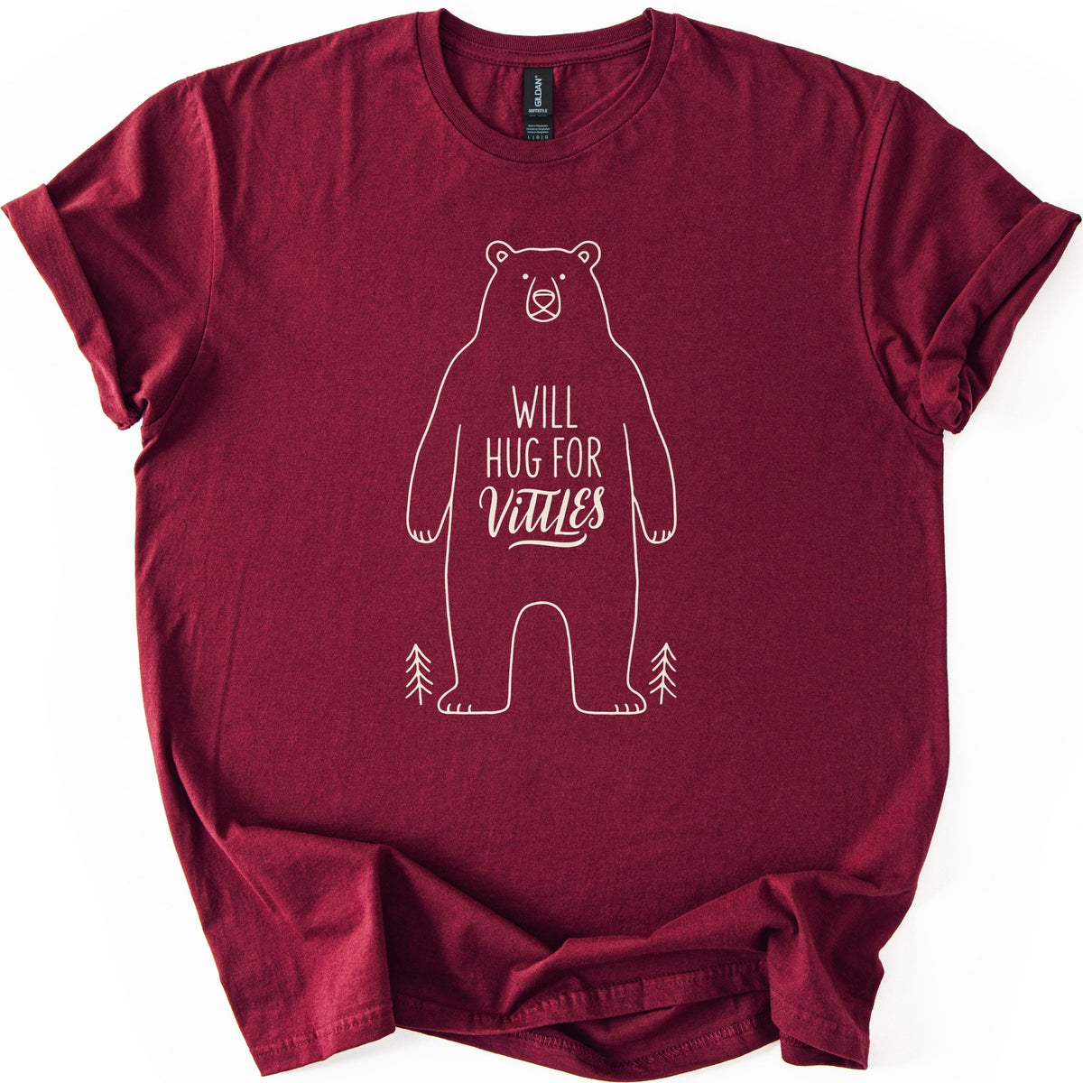 Will Hug For Vittles Bear Comfort Colors T-shirt in Maroon, laid flat. A cream line drawing of a standing bear with the words WILL HUG FOR Vittles on its belly and a small pine tree at each foot. The shirt has rolled sleeves and lies on a white background.