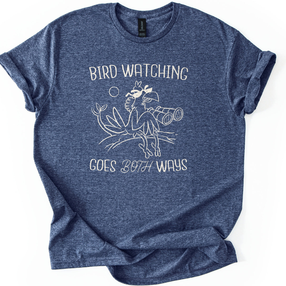 Birds Watch Back Birder Comfort Colors T-shirt in Heather Navy, laid flat. Cream line art of a cartoon bird in sunglasses perched on a branch beside a pair of binoculars, with a small sun, between the words Bird Watching Goes Both Ways. Sleeves rolled, on a white background.