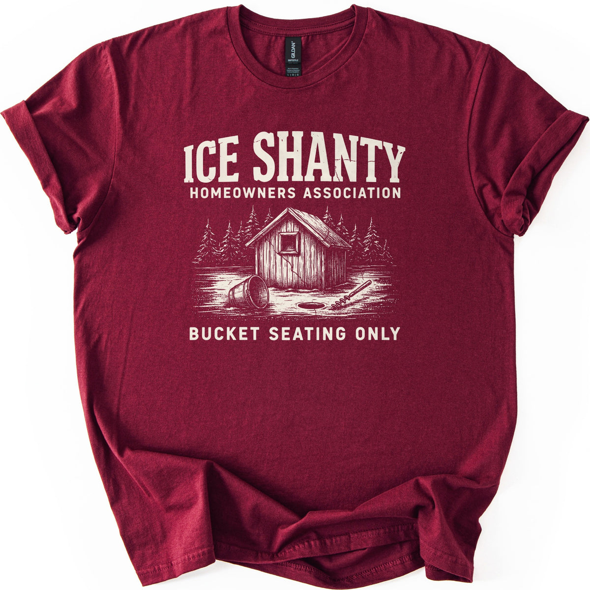 Ice Shanty Homeowners Association Comfort Colors T-shirt in Maroon, laid flat. Cream print reads ICE SHANTY, HOMEOWNERS ASSOCIATION above a sketch of a wooden ice shack among pines with a tipped bucket, ice hole and auger, then BUCKET SEATING ONLY. Sleeves cuffed, on white.