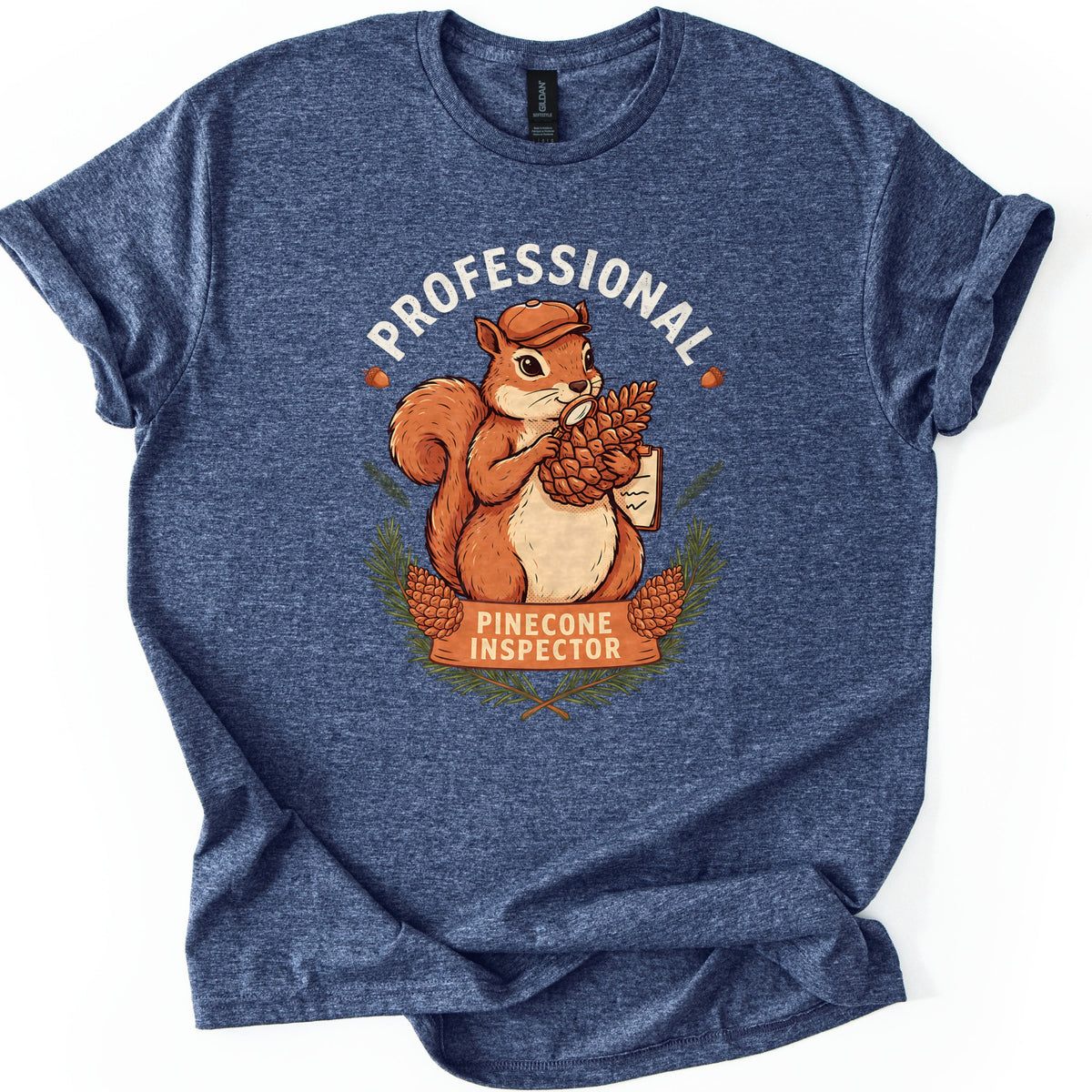 Professional Pinecone Inspector Comfort Colors T-shirt in Heather Navy, laid flat. A squirrel in a cap inspects a pinecone with a magnifying glass under the arched word Professional in white, above a banner reading Pinecone Inspector framed by pine branches. Sleeves are cuffed on a white surface.