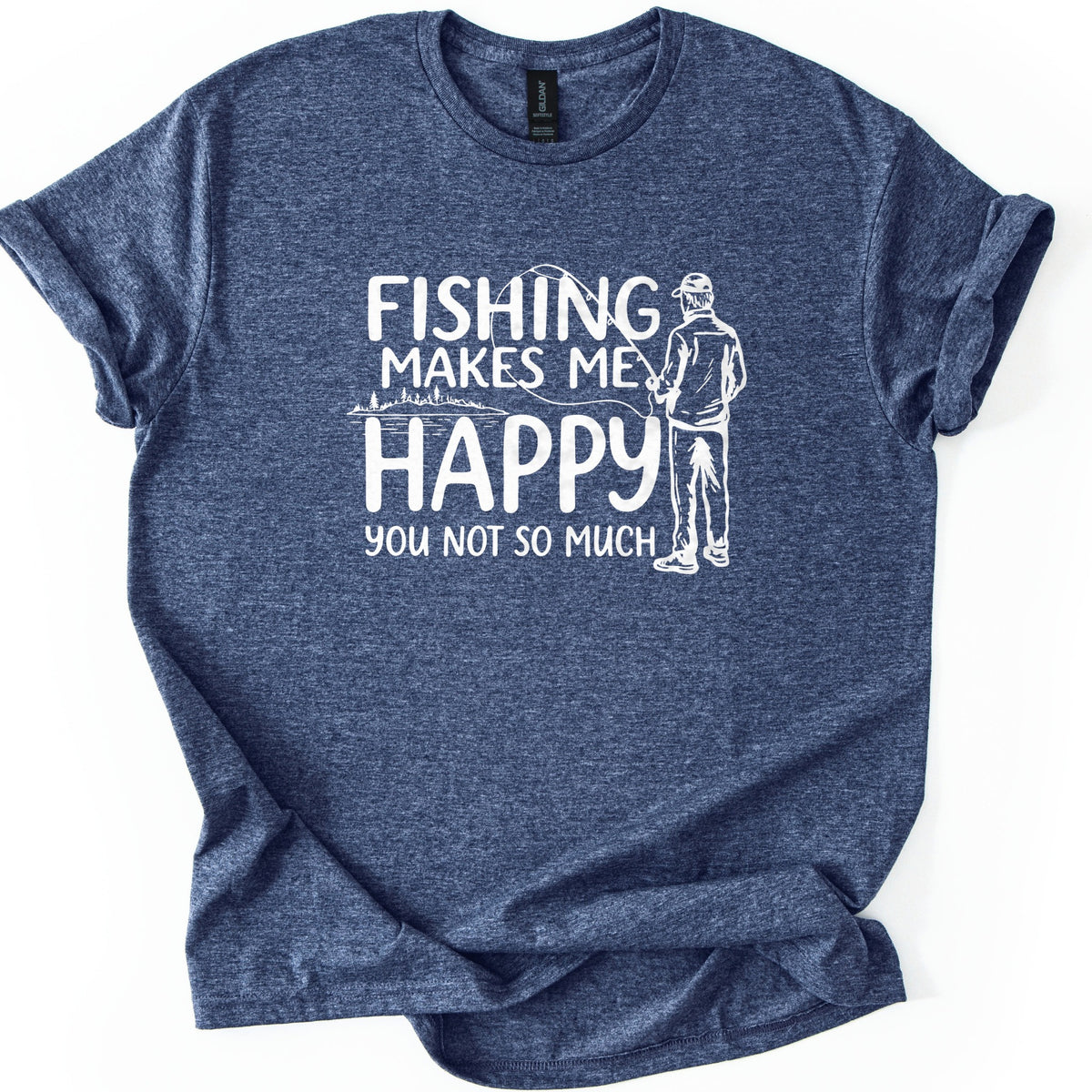 Fishing Makes Me Happy Comfort Colors T-shirt in Heather Navy, laid flat. White text reads Fishing Makes Me Happy, You Not So Much, beside a sketch of a man in a cap casting a rod from behind and a small lake lined with pine trees. Sleeves are rolled on a white background.