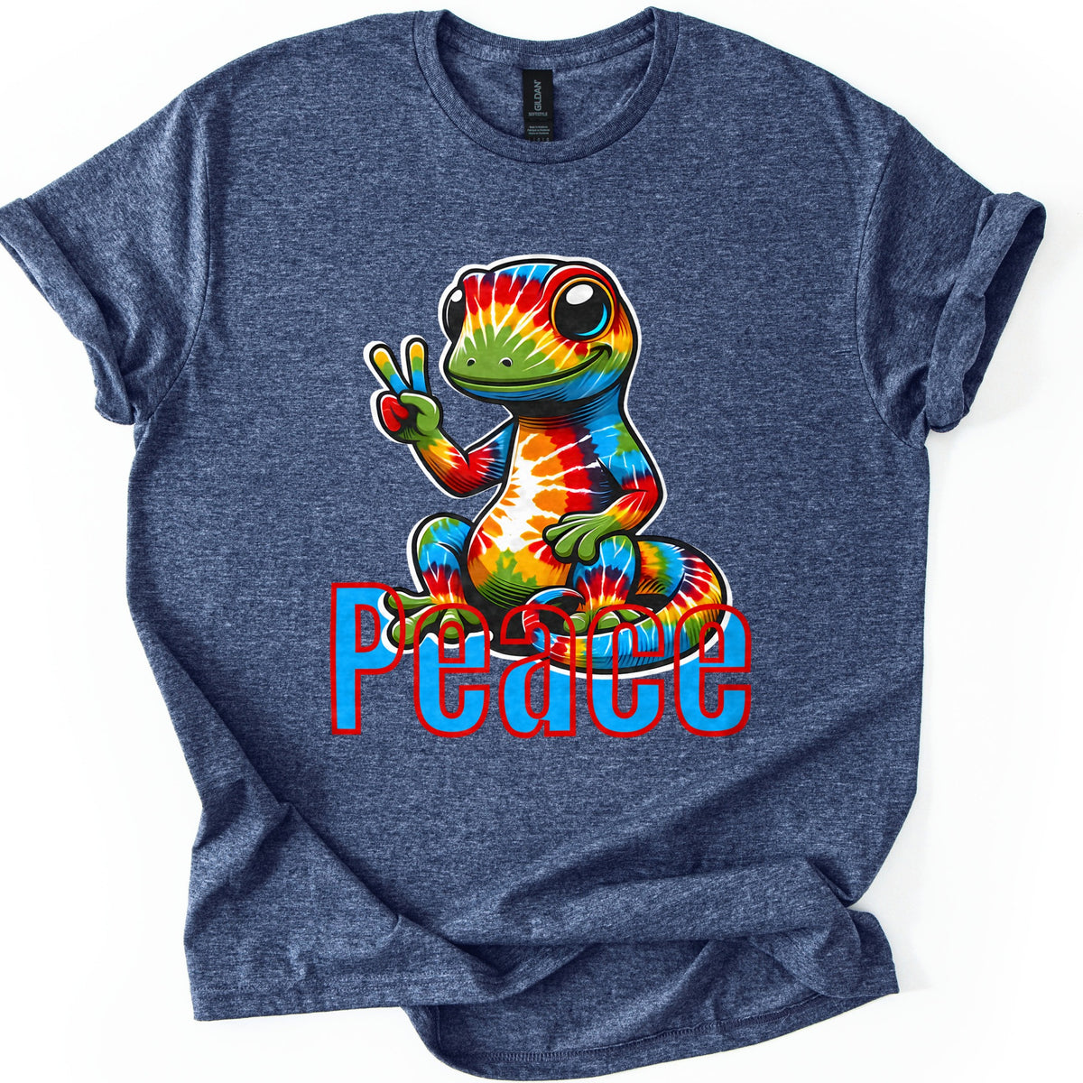 Rainbow Lizard Peace Comfort Colors T-shirt in Heather Navy, laid flat. A smiling cartoon lizard with tie-dye rainbow skin sits on its curled tail and flashes a peace sign above the word Peace in blue letters outlined in red. Cuffed sleeves on a white background.