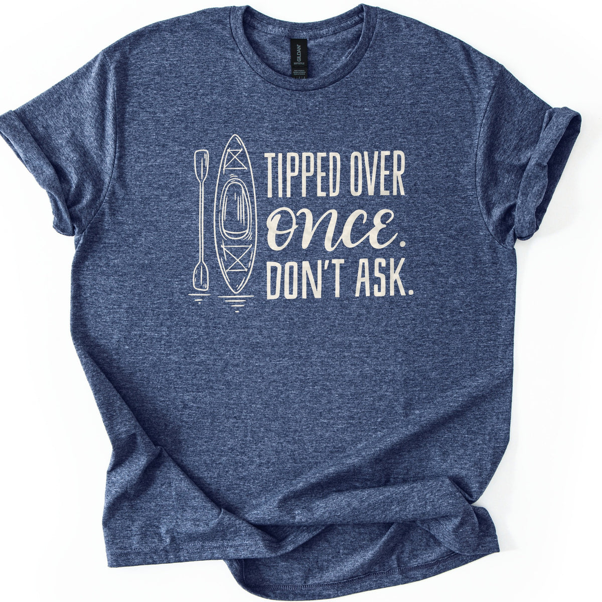 Tipped Over Once Kayak Comfort Colors T-shirt in Heather Navy, laid flat. A cream line drawing of an upright kayak and paddle with water ripples sits beside the words Tipped Over Once. Don't Ask., with Once in script. The shirt has cuffed sleeves on a white background.