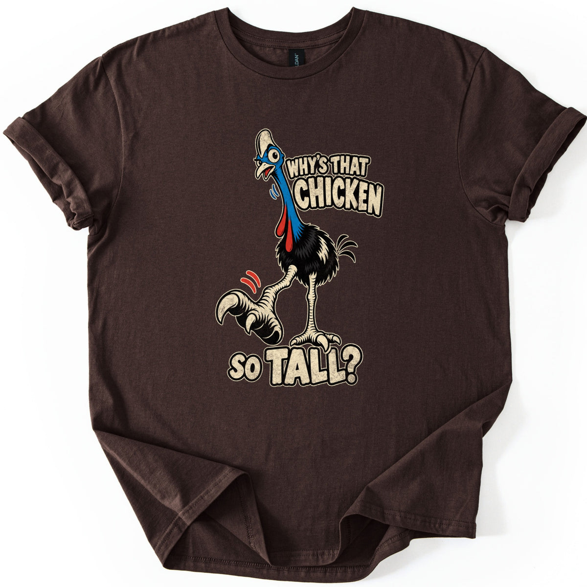 Why's That Chicken So Tall Comfort Colors T-shirt in Dark Chocolate, laid flat. A wide-eyed cartoon cassowary with a white crest, blue neck and red wattles lifts a huge clawed foot under the words Why's That Chicken So Tall? The shirt lies on white with rolled sleeves and a curled hem.