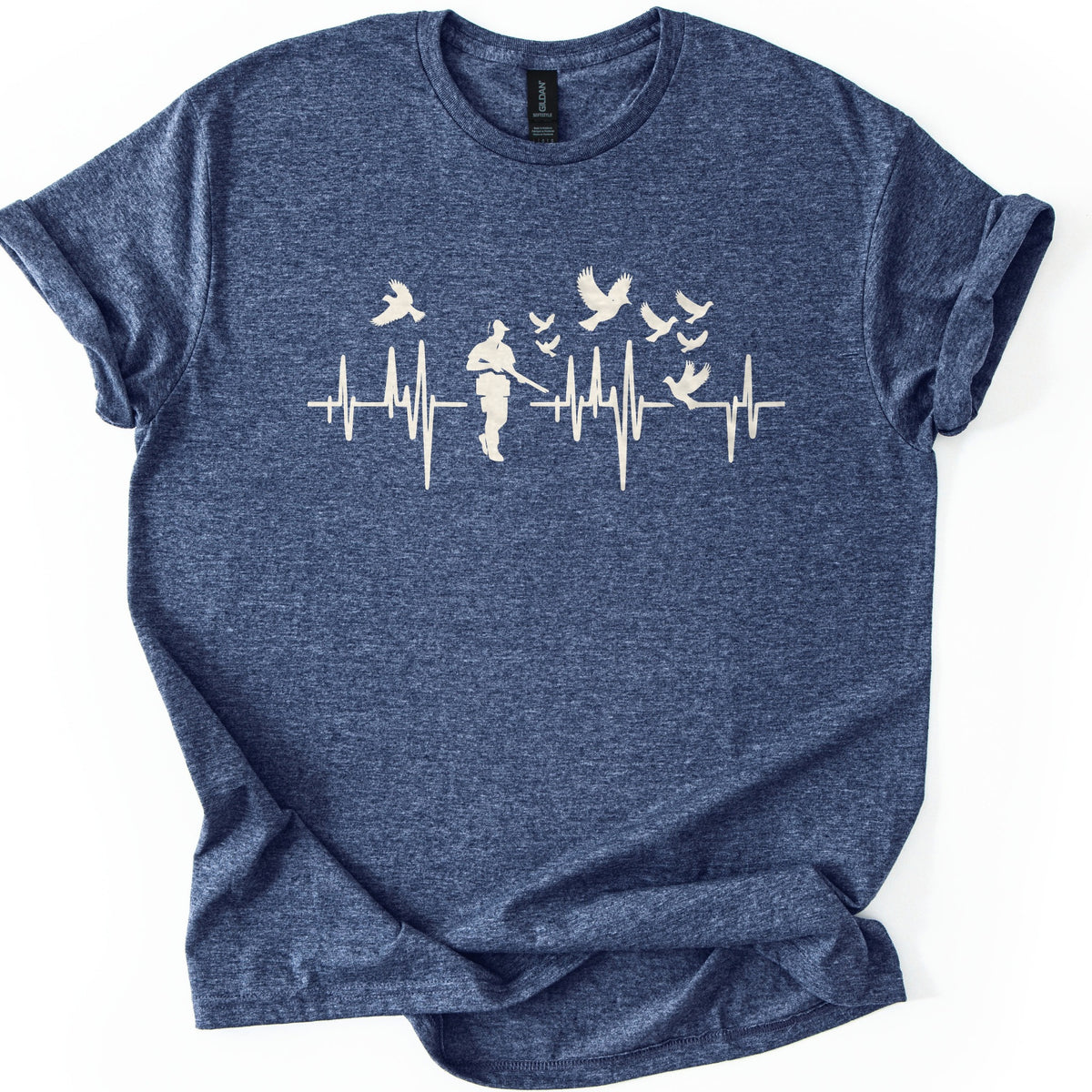 Bird Hunter Comfort Colors T-shirt in Heather Navy, laid flat. A cream heartbeat line crosses the chest around a silhouetted hunter in a cap holding a shotgun, with birds flying above and one perched on the line. No words. Cuffed sleeves on a white background.