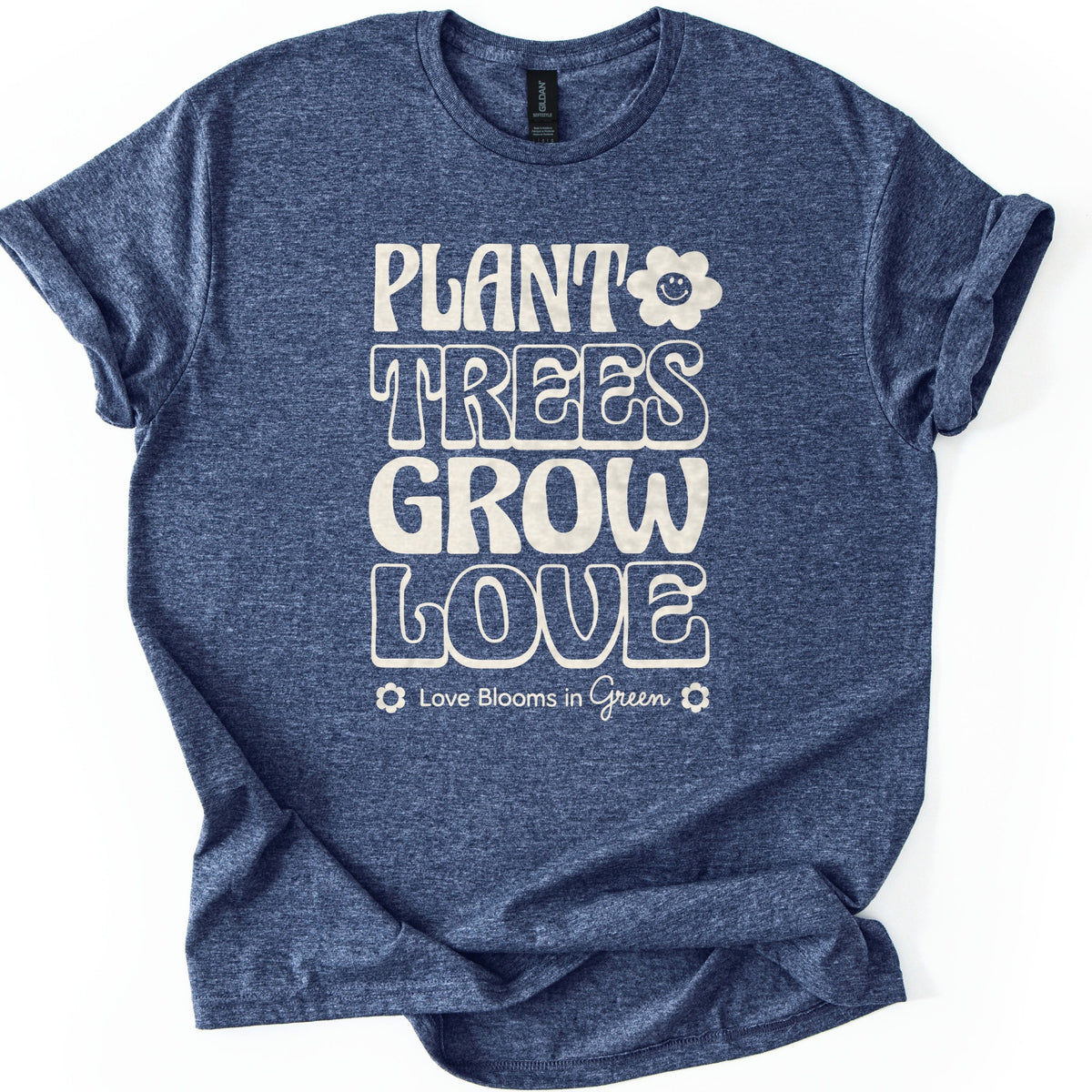 Plant Trees Grow Love Comfort Colors T-shirt in Heather Navy, laid flat. Cream retro bubble letters read Plant Trees Grow Love, with a smiling daisy beside Plant and Love Blooms in Green between two small flowers below. Sleeves are rolled on a white background.