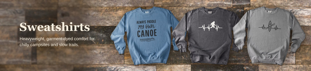 Comfort Colors crewneck sweatshirts with outdoor-themed Woodsy prints against rustic barnwood